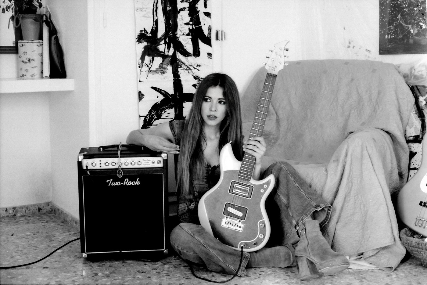 Mar Sánchez sentada junto a su guitarra eléctrica y su amplificador Two-Rock, en blanco y negro